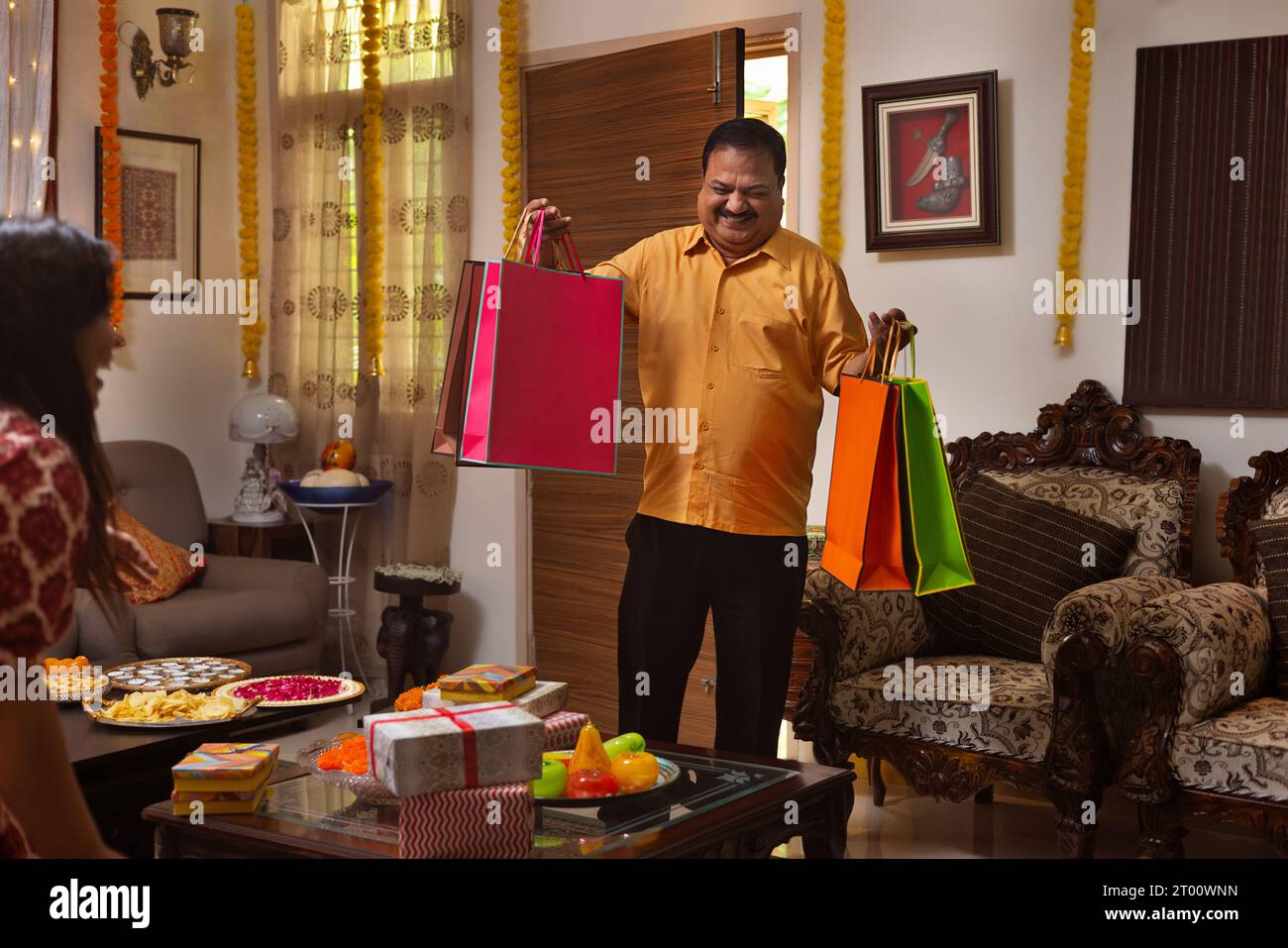 L'uomo è felice di entrare in casa con regali e borse per la sua famiglia, durante il festival di Diwali Foto Stock