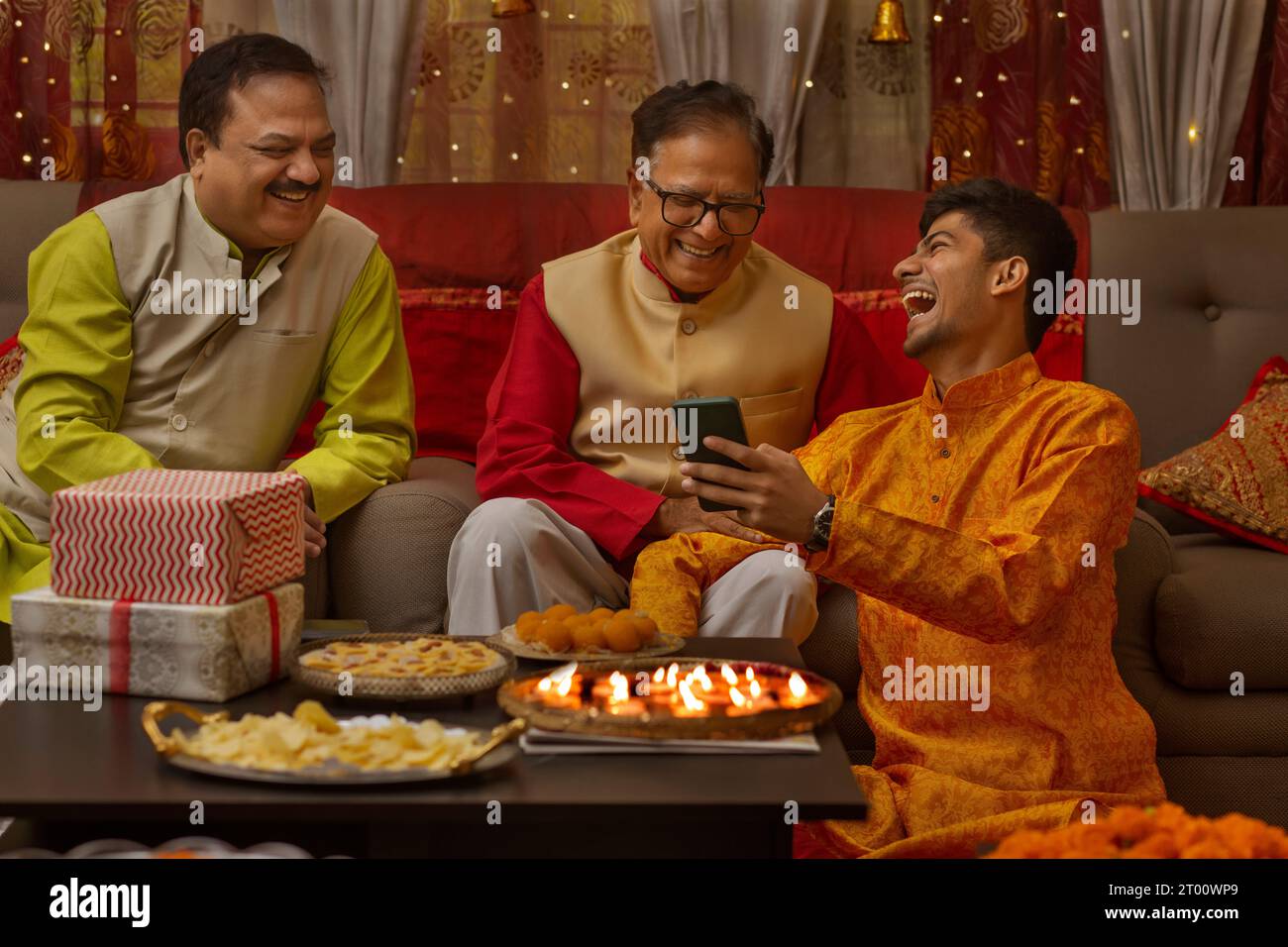 La famiglia si diverte in occasione di Diwali sedendosi insieme nel soggiorno Foto Stock