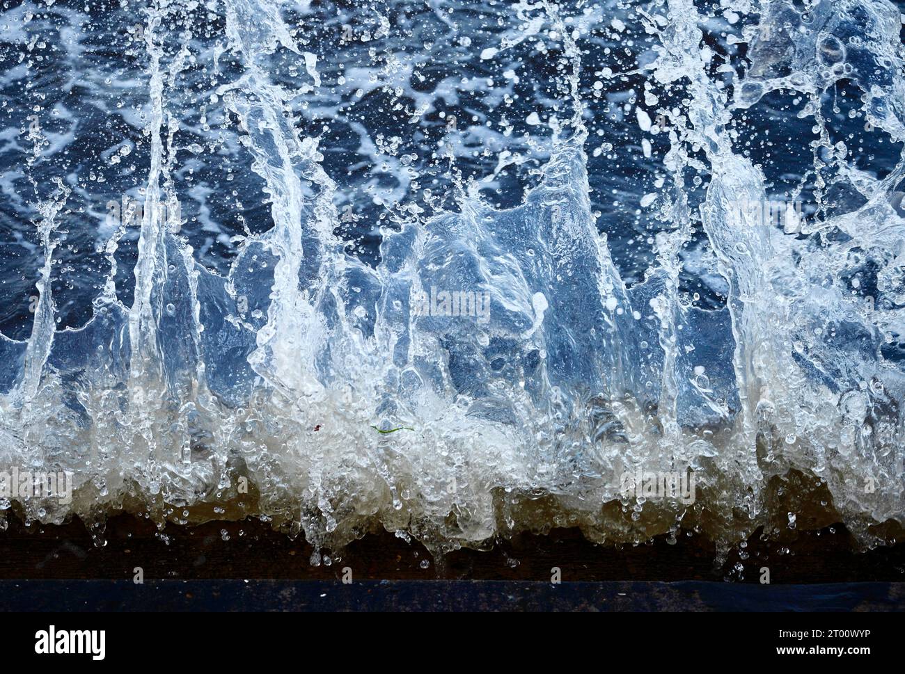 Acqua di mare che schizza contro le pareti del mare. Foto Stock