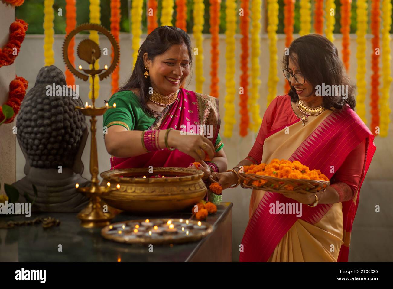 Suocera e nuora decorano casa con fiori e lampade in occasione di Diwali Foto Stock