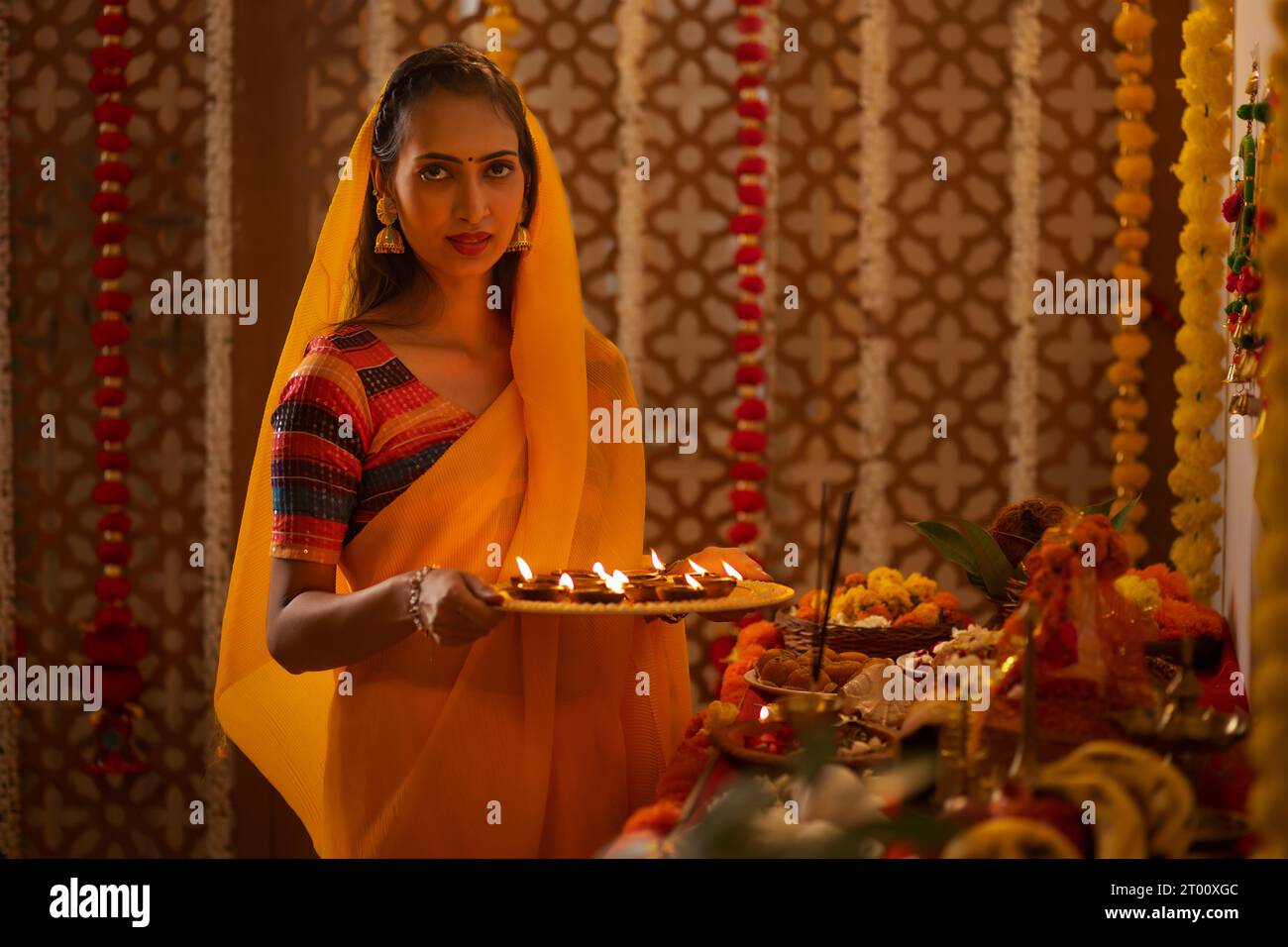 Ritratto di una donna indiana che tiene un piatto di diya e che adora Dio su Diwali Foto Stock