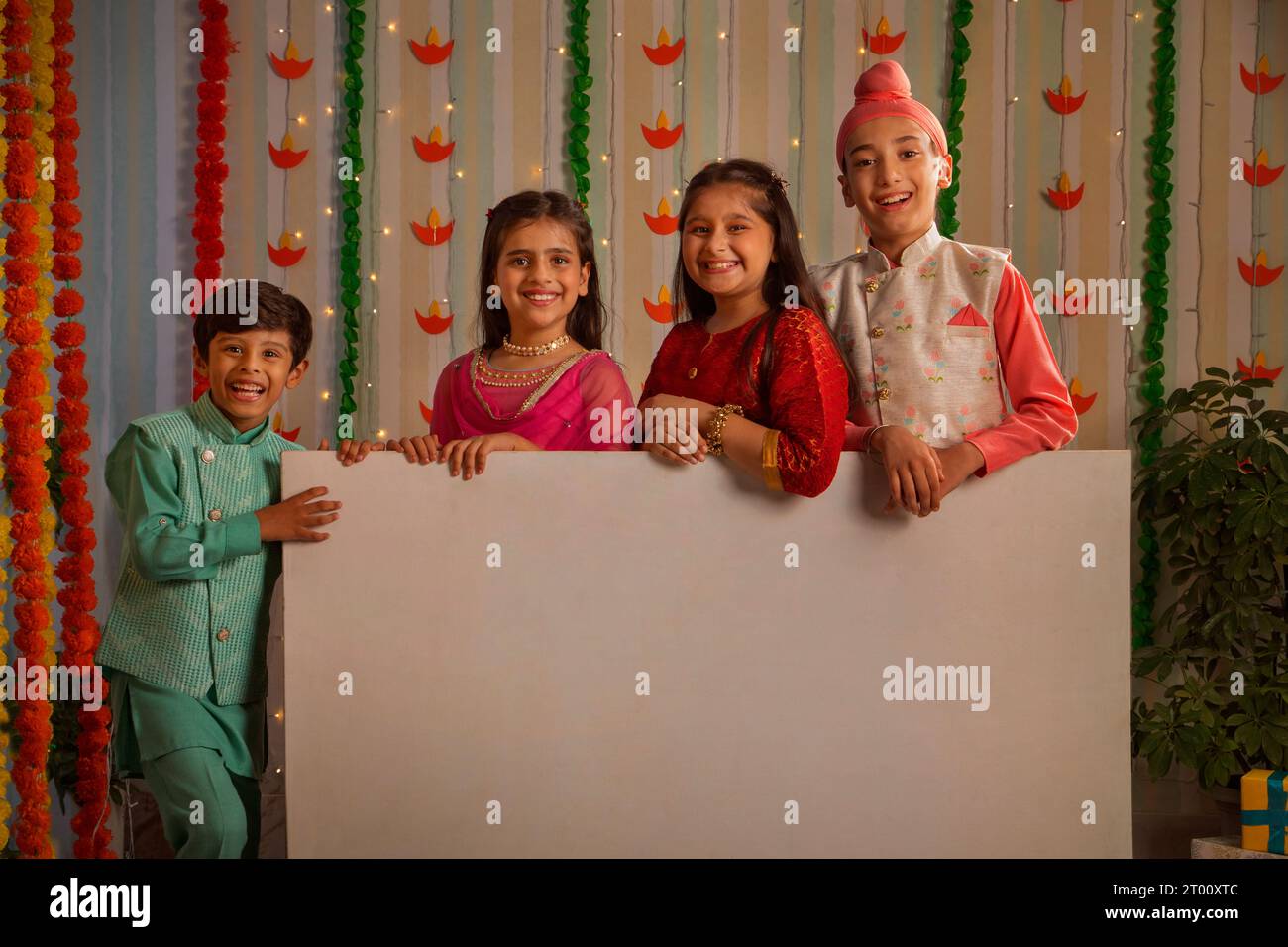 I bambini indossano abiti tradizionali tenendo in mano una lavagna bianca che guarda la macchina fotografica e sorridono durante le celebrazioni di Diwali Foto Stock