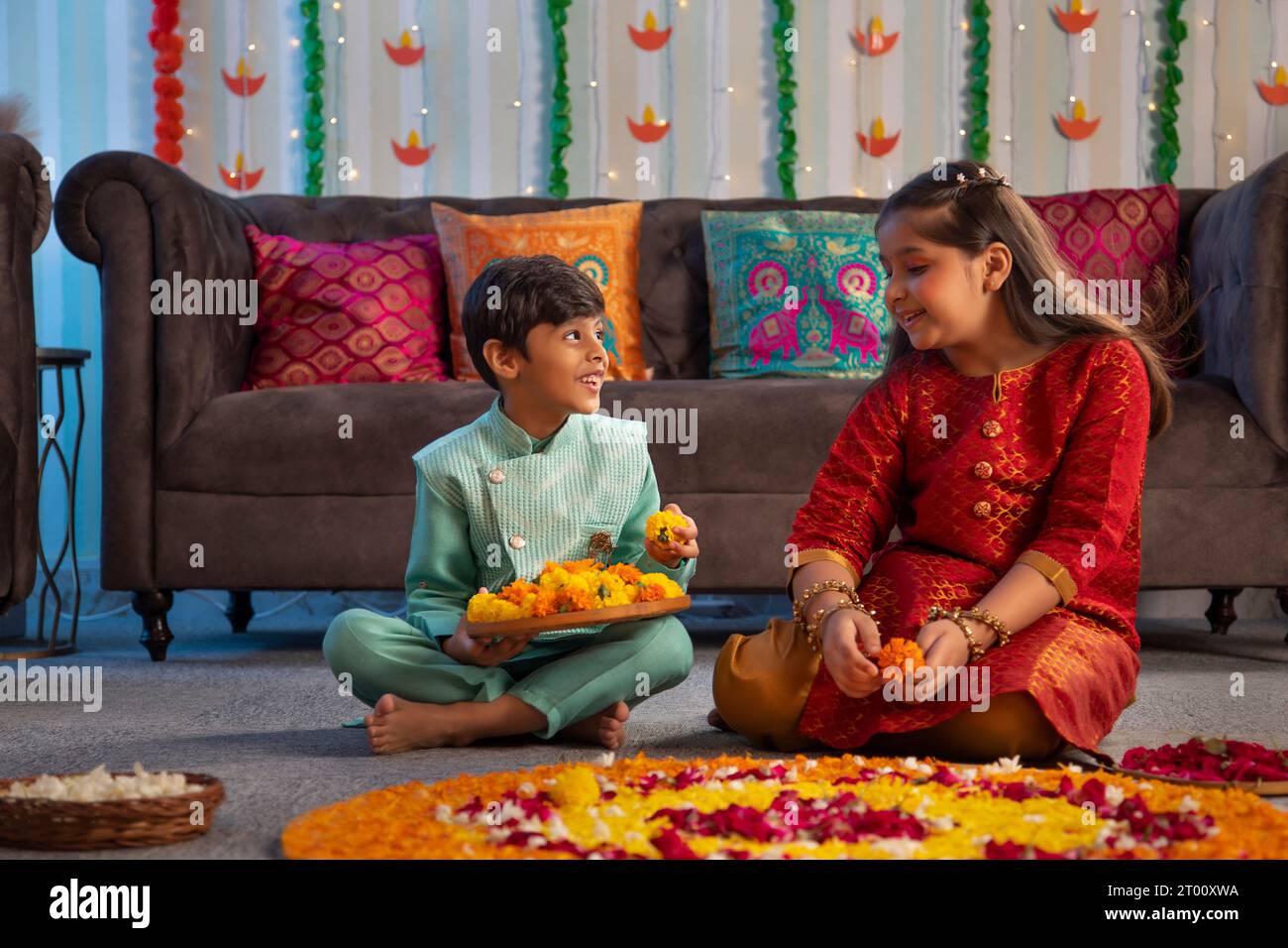 Fratello e sorella decorano il pavimento con fiori (Rangoli) in occasione di Diwali Foto Stock