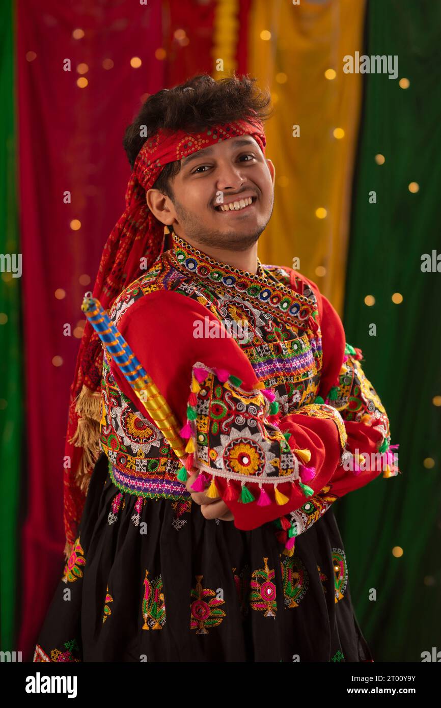 Ritratto di un giovane felice in kedia e dhoti che tiene dandiya durante le celebrazioni Navratri Foto Stock