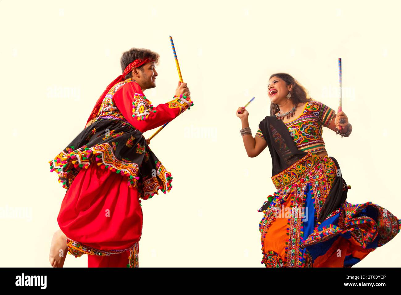 Una giovane coppia felice che esegue Dandiya Raas su sfondo nero, durante le celebrazioni di Navratri Foto Stock