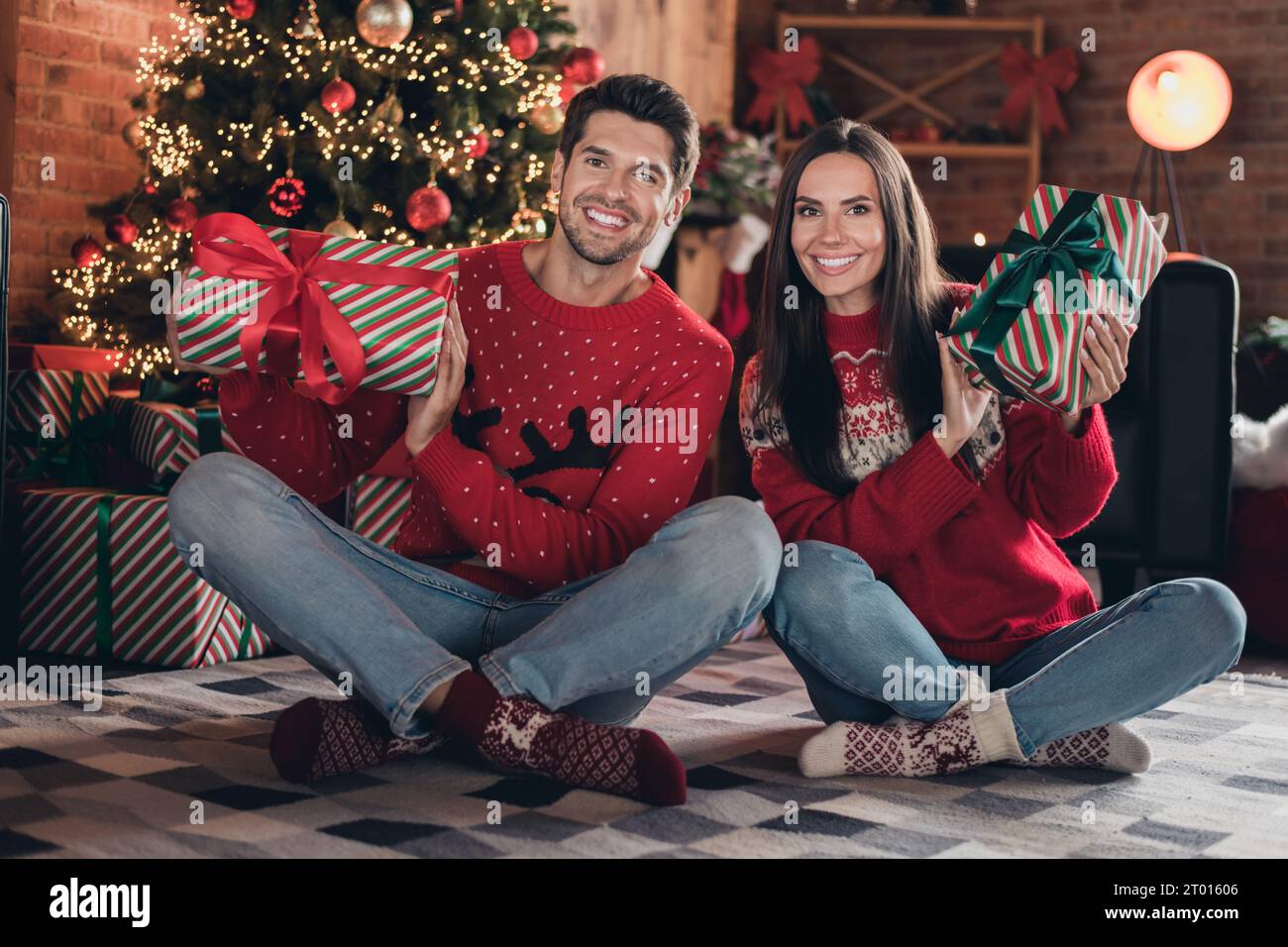 Foto integrale di un giovane padre di famiglia con una mamma che tiene due regali preparati per il simbolo di Natale dei bambini piccoli seduti nello studio di Capodanno Foto Stock