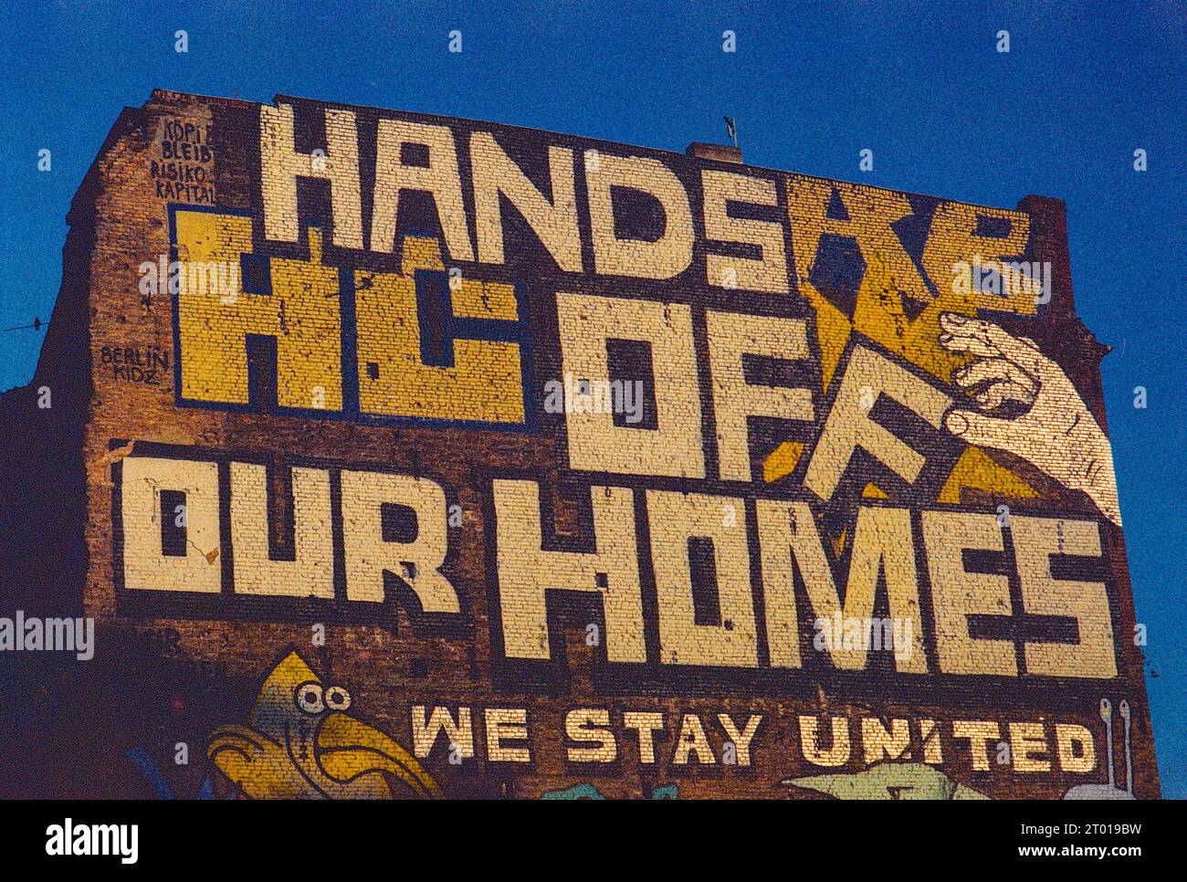 Enorme, attivista: Graffiti 'Hands of Our Homes' sul lato di un edificio domestico a Kopernicker Strasse, berlino, Germania. Mostra un certo attivismo e opposizione nella città verso la gentrificazione del vicinato e l'ascesa dei broker immobiliari che realizzano molti profitti. Immagine ripresa su una vecchia pellicola Kodak analogica. Foto Stock