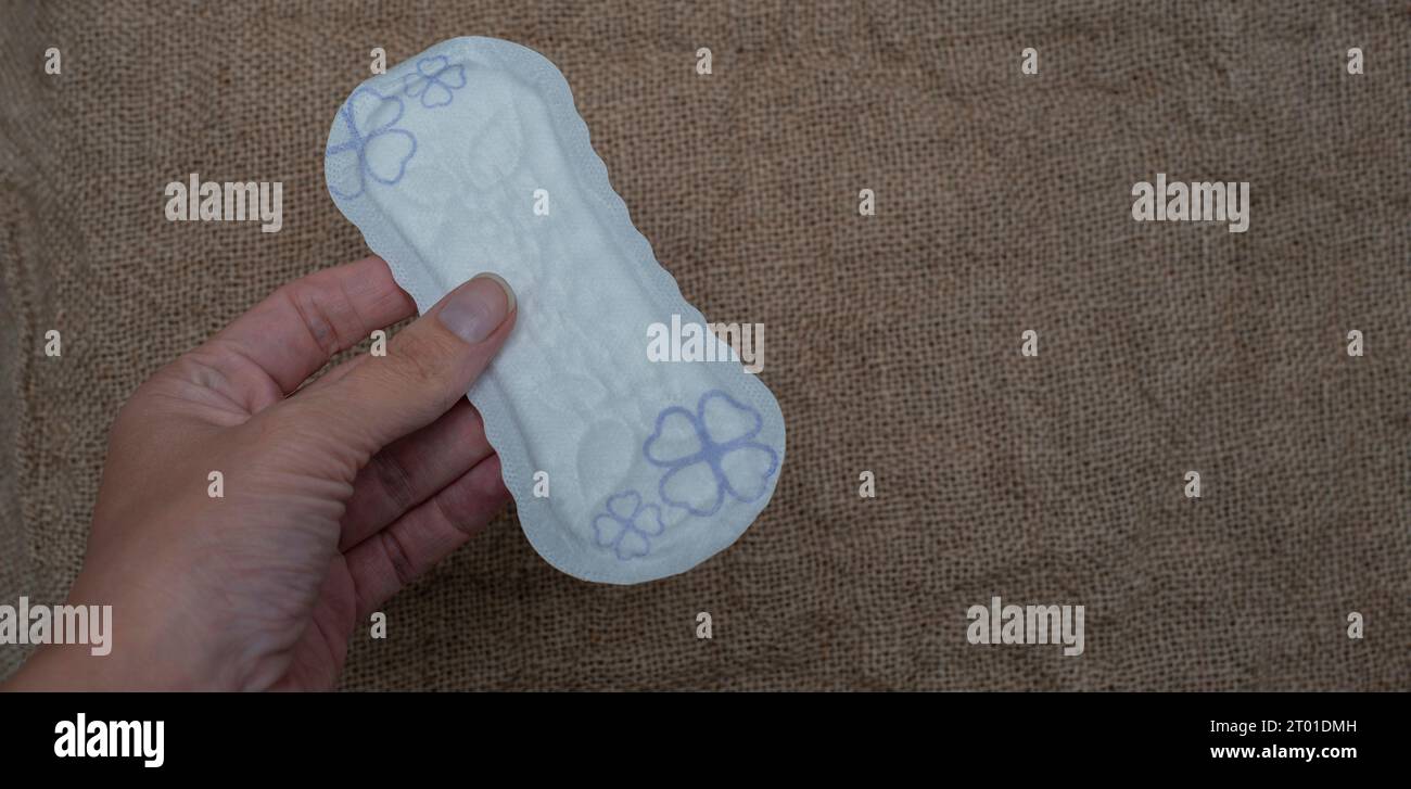 Tamponi igienici da donna su sfondo marrone. Donna che tiene la mano ogni giorno. concetto di igiene Foto Stock