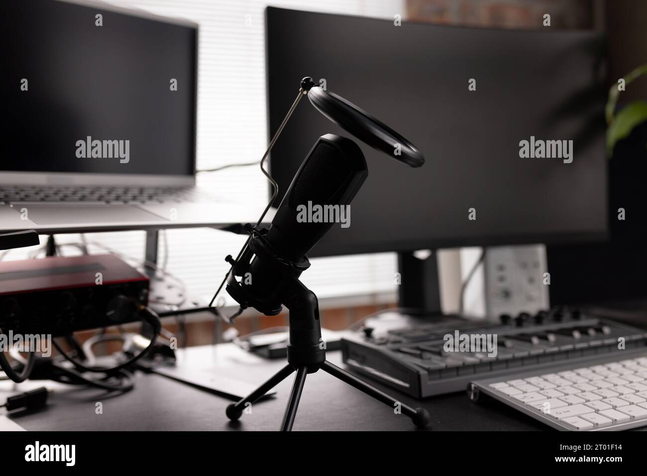 Configurazione podcasting con computer, tastiera e microfono sulla scrivania a casa Foto Stock