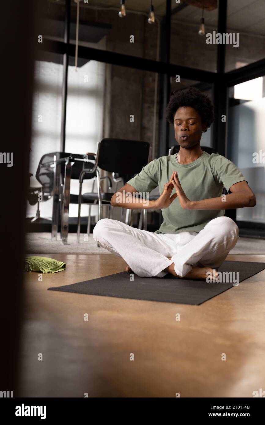 Uomo afro-americano felice e rilassato che pratica yoga respirazione profonda seduto a casa, spazio fotocopie Foto Stock