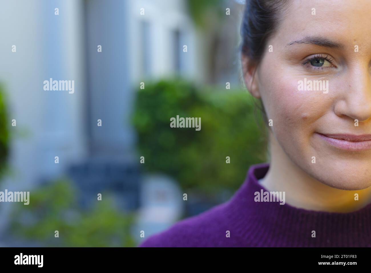 Mezza faccia di una donna caucasica felice in piedi di fronte a casa in giardino Foto Stock