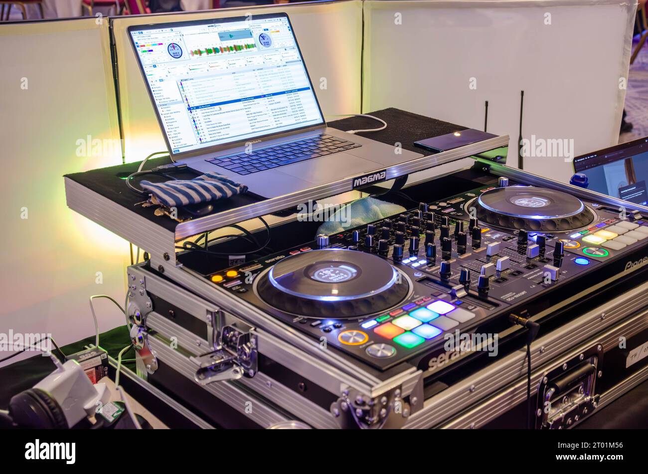 Un DJ con postazione di mixaggio e un computer portatile per ascoltare musica e divertirsi durante una festa Foto Stock