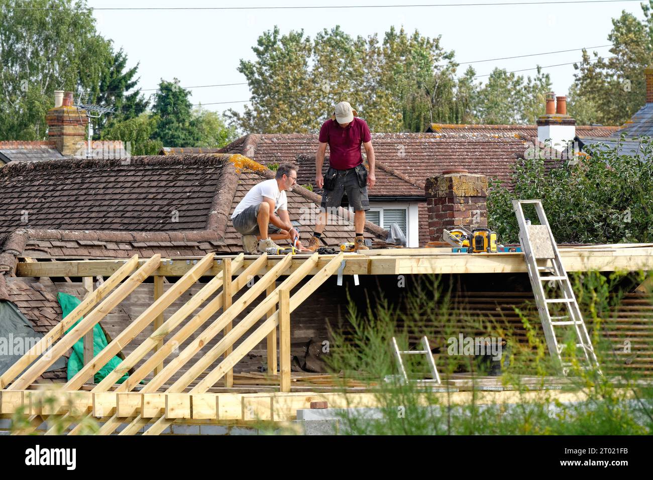 Costruttori che lavorano su un'estensione del tetto di un bungalow suburbano a Shepperton, Surrey, Inghilterra, Regno Unito Foto Stock