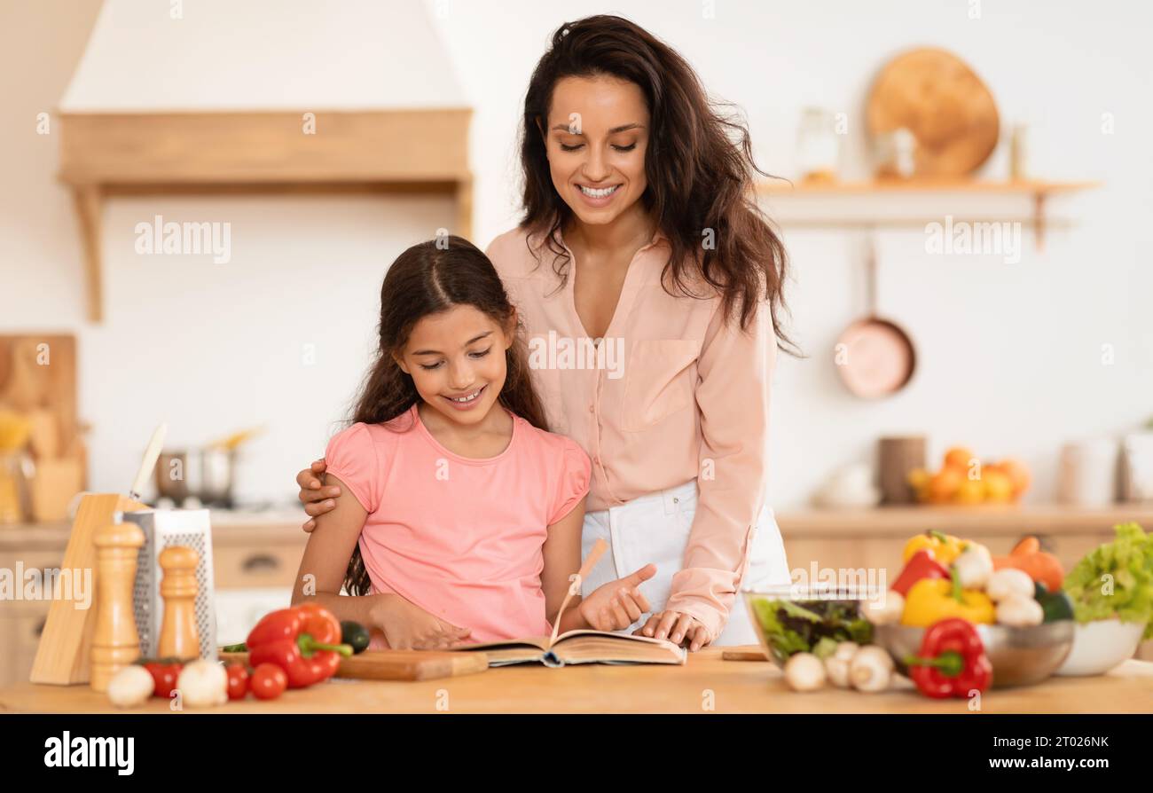 Allegra mamma e figlia che cucinano leggendo ricette Libro in cucina Foto Stock