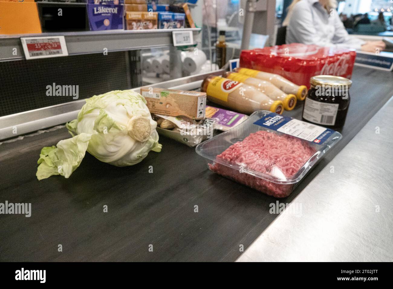 Merci sul nastro trasportatore del supermercato in attesa della cassa di cassa. Foto Stock