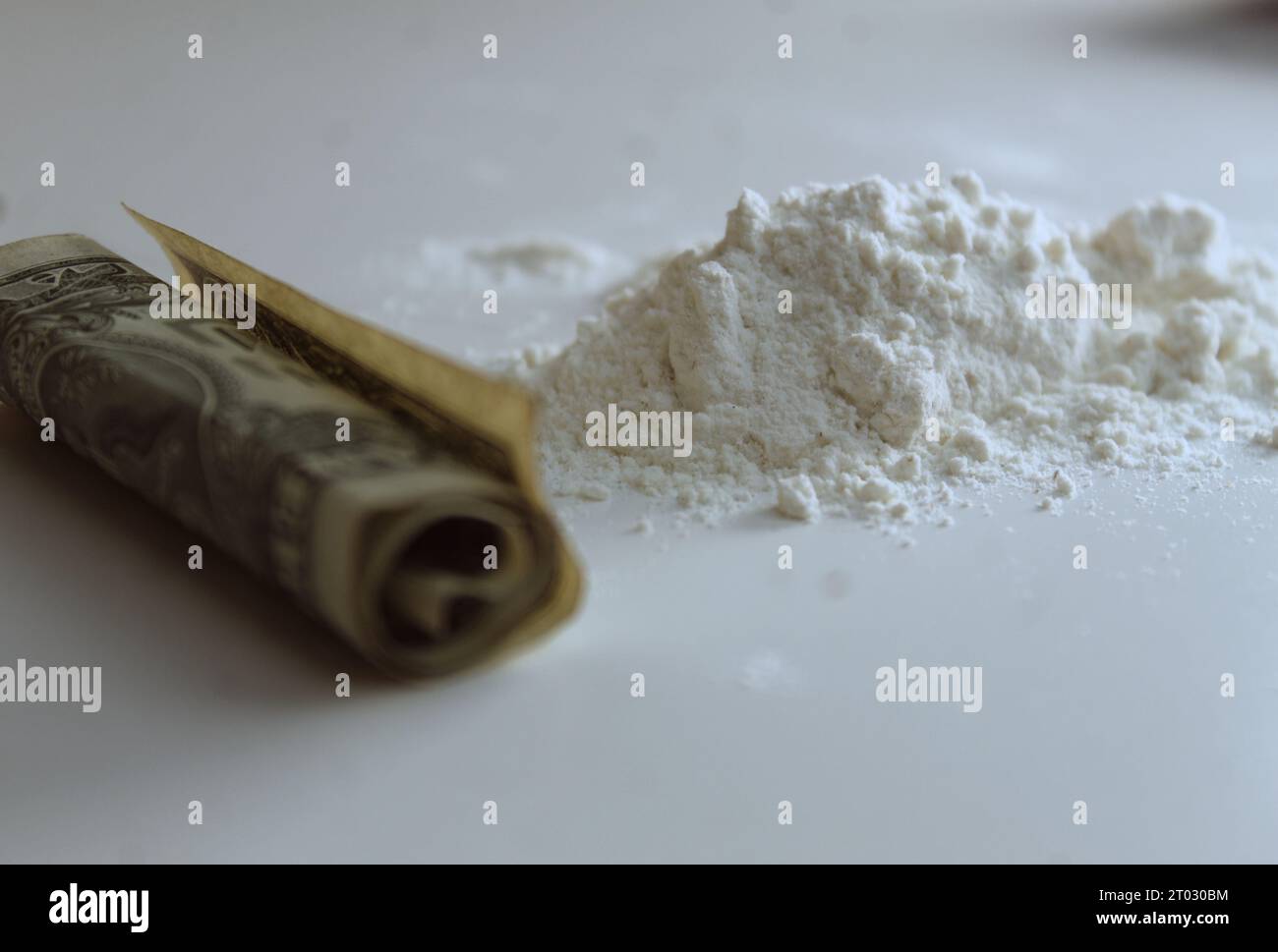 Una foto della cocaina della droga accanto a una pila di soldi su una scrivania. Foto Stock