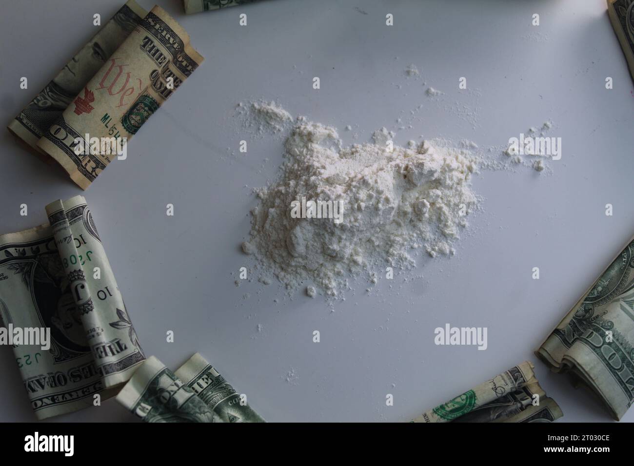 Una foto della cocaina della droga accanto a una pila di soldi su una scrivania. Foto Stock