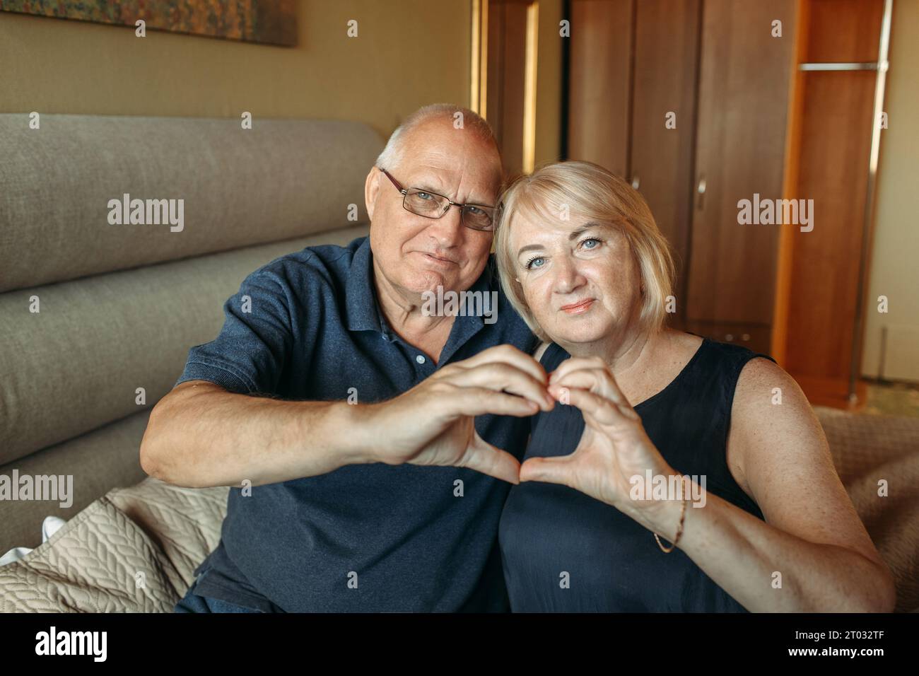 Una coppia anziana mostra un cuore con le mani come segno di amore per i propri cari. Primo piano. Foto Stock