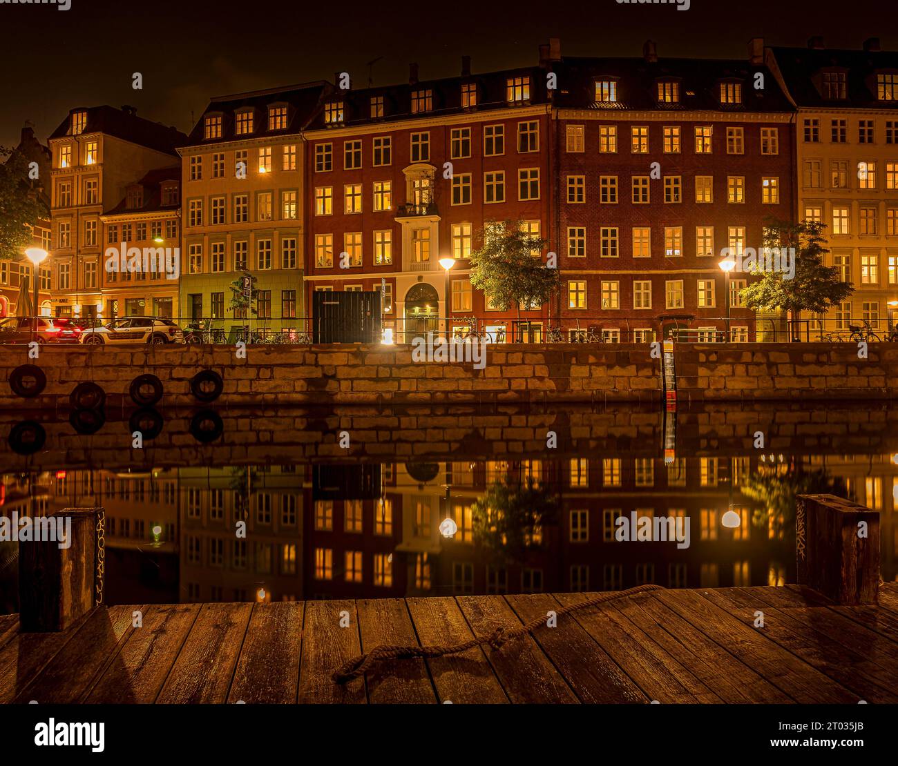 Molo di legno vicino al canale Slotsholm a Copenaghen, dove le case si riflettono nell'acqua calma di notte, Danimarca, 2 ottobre 2023 Foto Stock