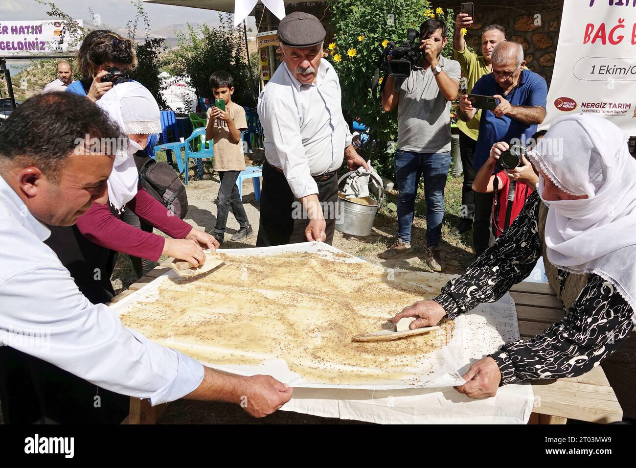 Diyarbakir, Turchia. 1 ottobre 2023. Due donne curde preparano un pesticida diffondendo su un panno l'acqua di melassa, che viene bollita e mescolata con la farina. I tradizionali festival vintage si tenevano nella storica città di Diyarbakir, dove vivono principalmente curdi. Coloro che hanno assistito al festival che si tiene nel villaggio di Kanisipi nel distretto di Silvan hanno guardato le tappe fino a quando l'uva è stata raccolta e trasformata in salsiccia con interesse. (Foto di Mehmet Masum Suer/SOPA Images/Sipa USA) credito: SIPA USA/Alamy Live News Foto Stock