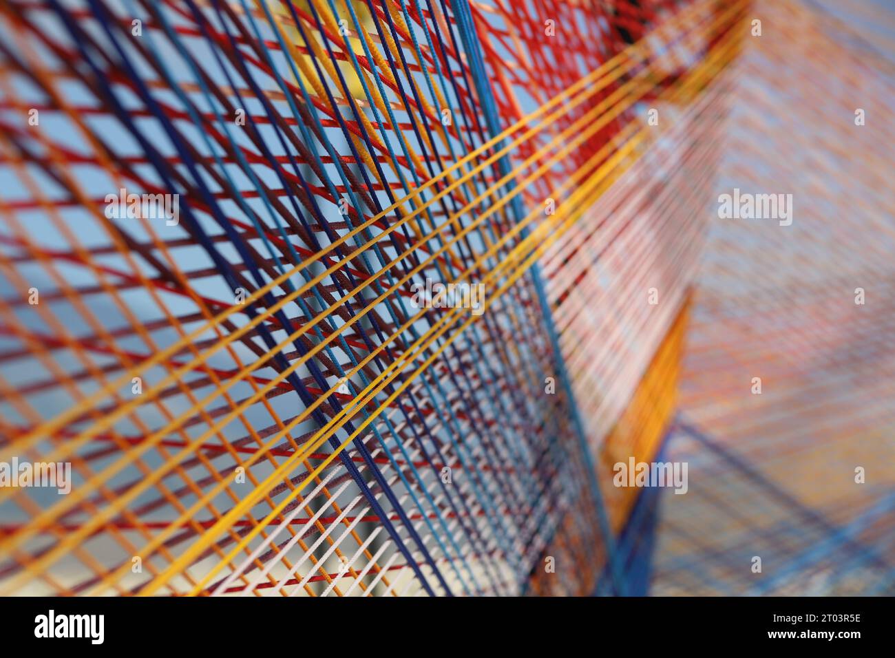 Un palcoscenico da esterno dal design artistico moderno ed esteticamente gradevole, realizzato con più corde intrecciate multicolori, fili o spago con uno sfondo montano. Foto Stock