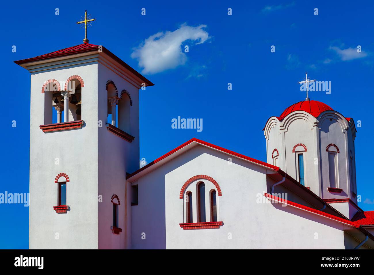 Chiesa rossa e bianca contro cielo blu con nuvole. Architettura religiosa Foto Stock