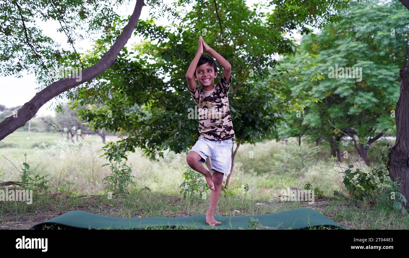 Ritratto di un bellissimo ragazzo che pratica yoga all'aperto. I bambini possono praticare yoga asana o esercizi ginnici. Bambini piccoli che meditano nel lotus po Foto Stock