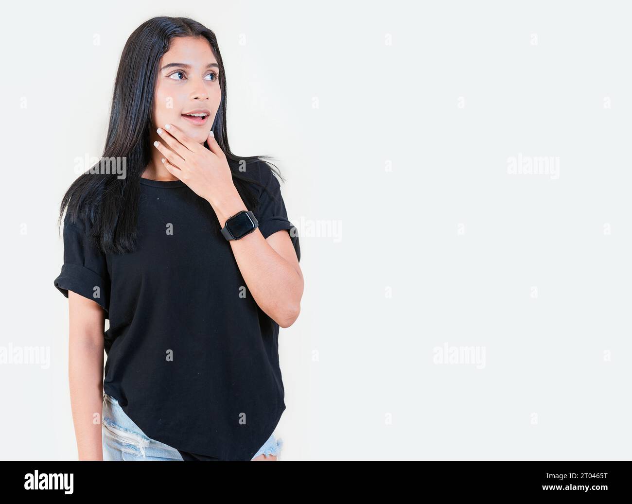 Sorpreso ragazza adolescente che guarda una pubblicità a Side. Sorpreso dalla ragazza latina che guarda una promozione a lato. Persone stupite con la mano sul mento Foto Stock