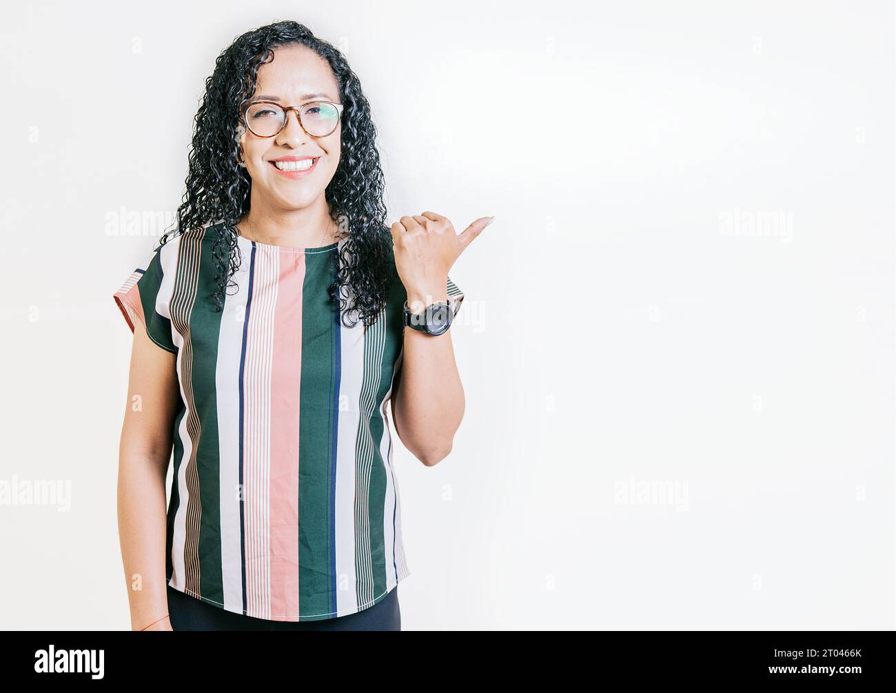 Sorridenti latini che puntano a uno striscione di lato. Felice donna latina che consiglia con le dita isolate. Allegra ragazza dai capelli ricci che indica un Foto Stock