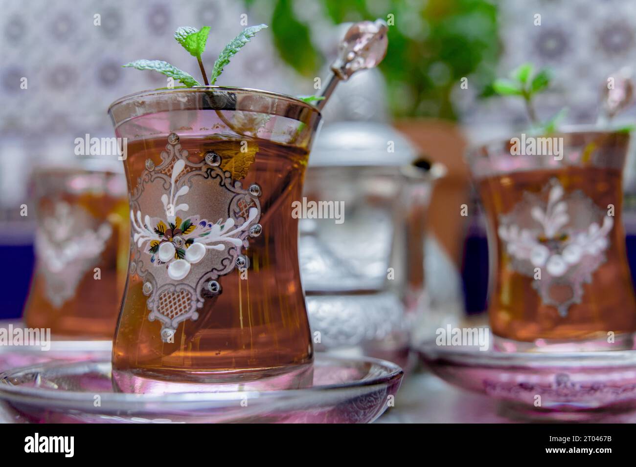 Tè moresco con menta, bevanda tradizionale marocchina in bicchieri di cristallo decorati, teiera argentata e ciotola da zucchero sullo sfondo Foto Stock