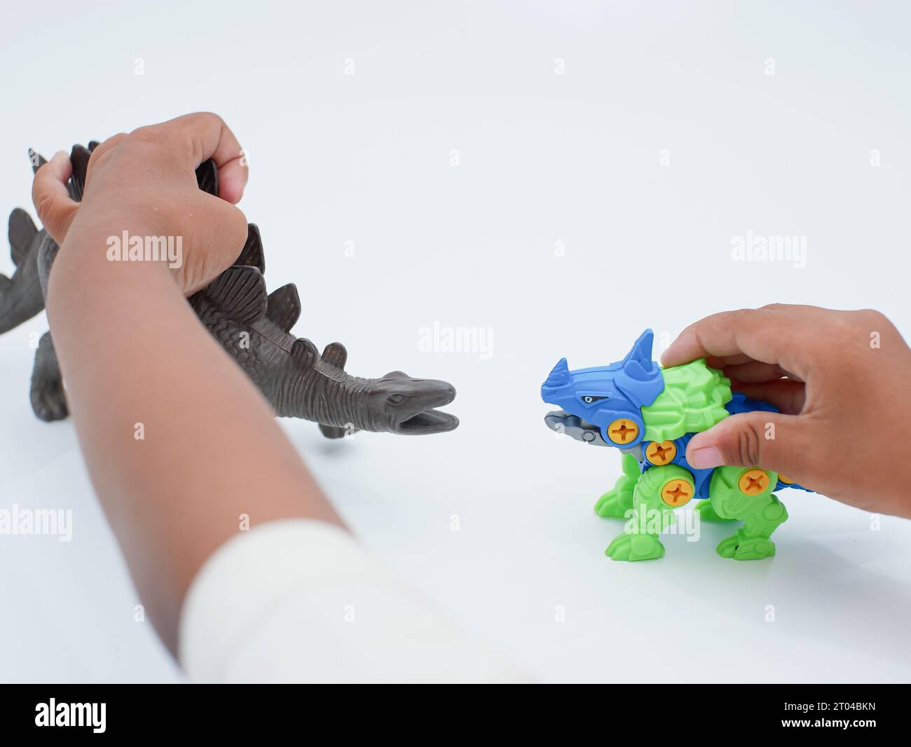 le mani dei bambini giocano a stegosaurus e centrosaurus, genere di dinosauro corazzato isolato su sfondo bianco Foto Stock