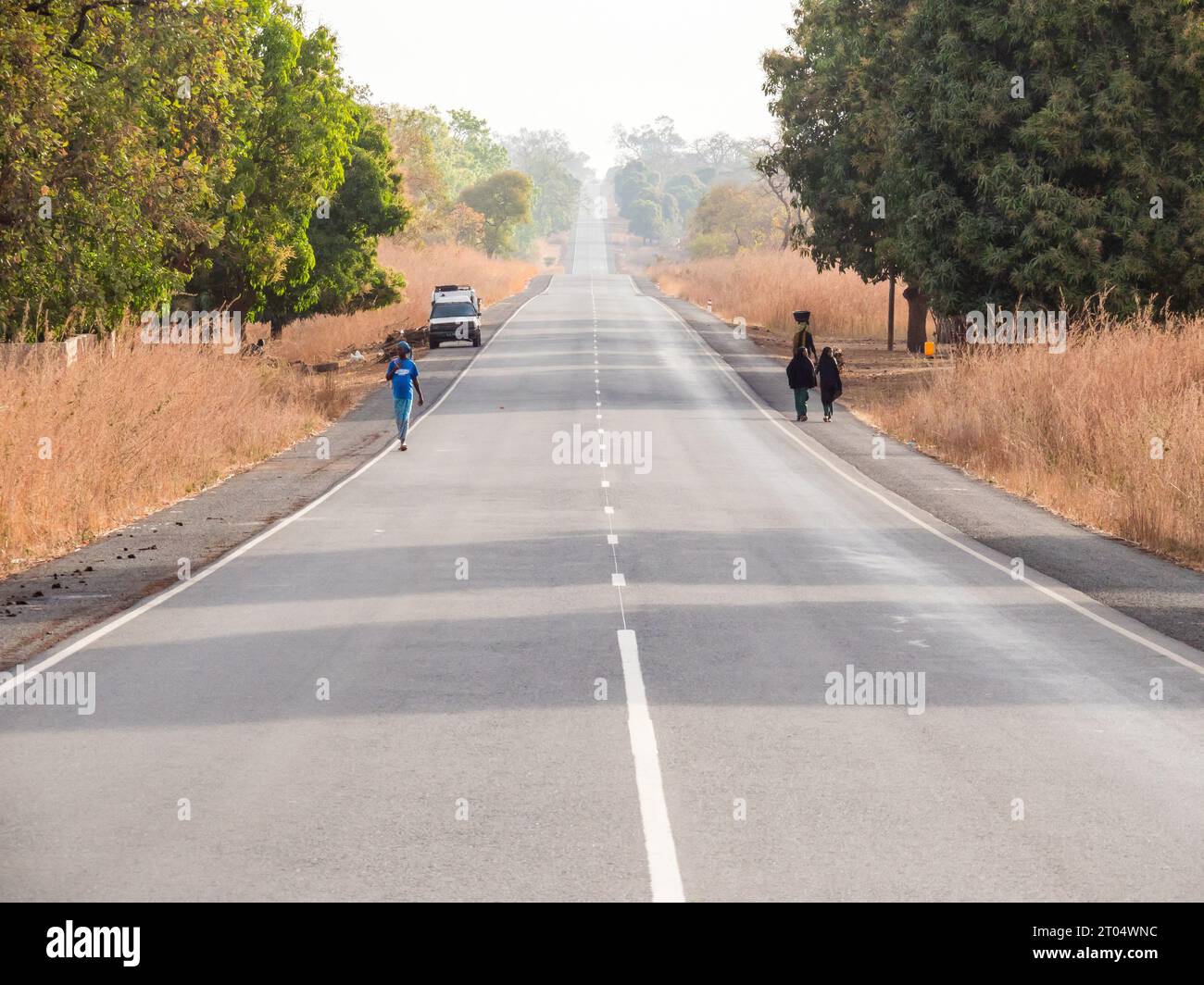 Gente che cammina lungo la strada principale, Gambia Foto Stock