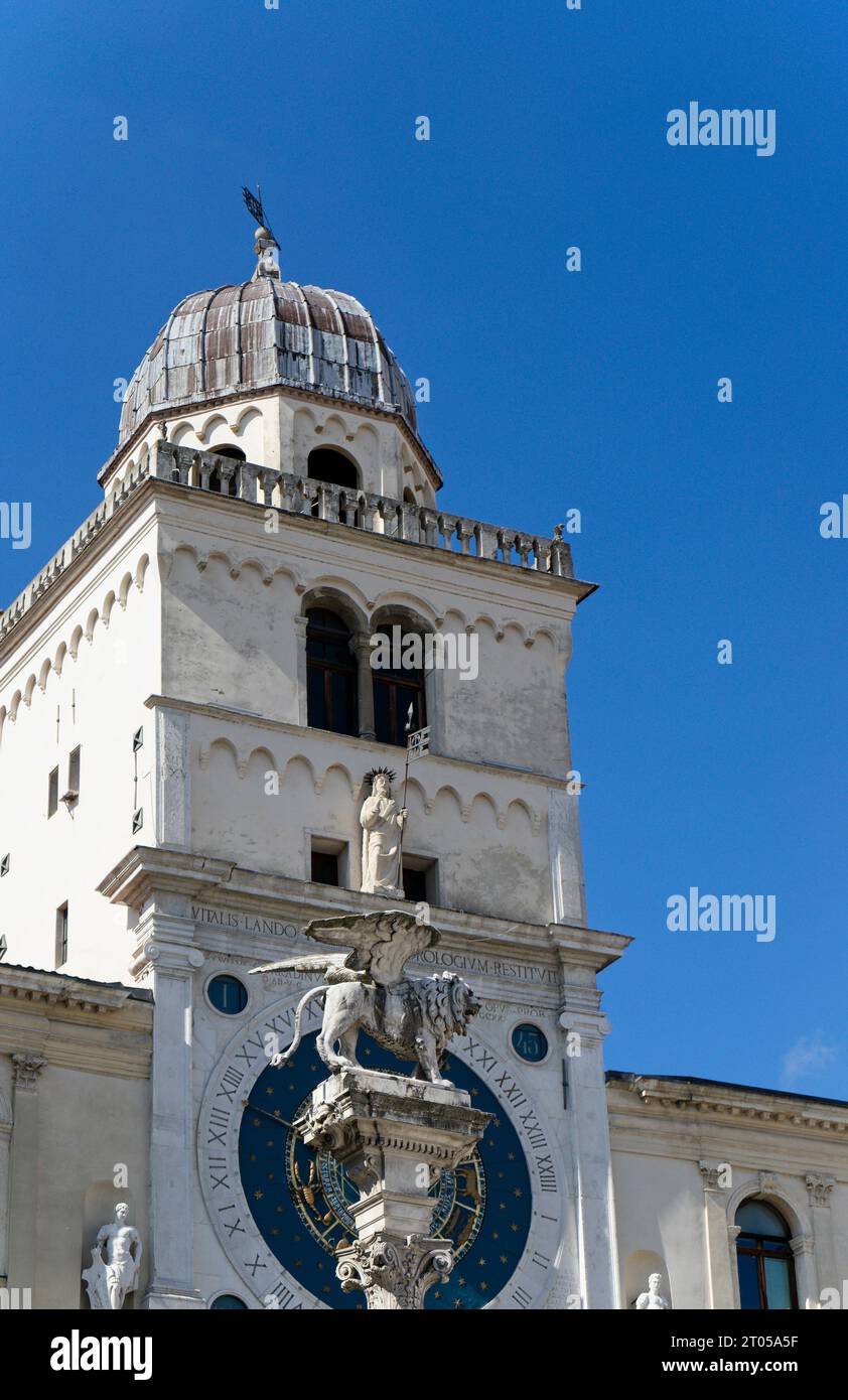 Primo piano della colonna con il Leone di St Segnate nel centro storico di Padova, sullo sfondo l'orologio astronomico medievale in Italia Foto Stock