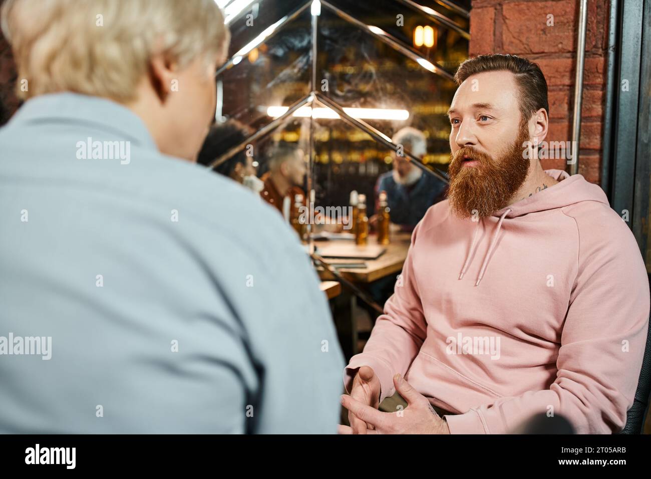 uomini tatuati barbuti che parlano con una donna di mezza età mentre condividono l'idea di un nuovo progetto di startup in un pub Foto Stock