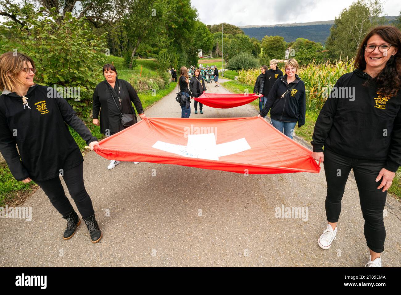 Gli abitanti del villaggio vestiti con costumi tradizionali prendono parte con orgoglio all'annuale parata delle mucche alpine nel villaggio di Ligniéres, sulle montagne del Giura, in Svizzera. Foto Stock