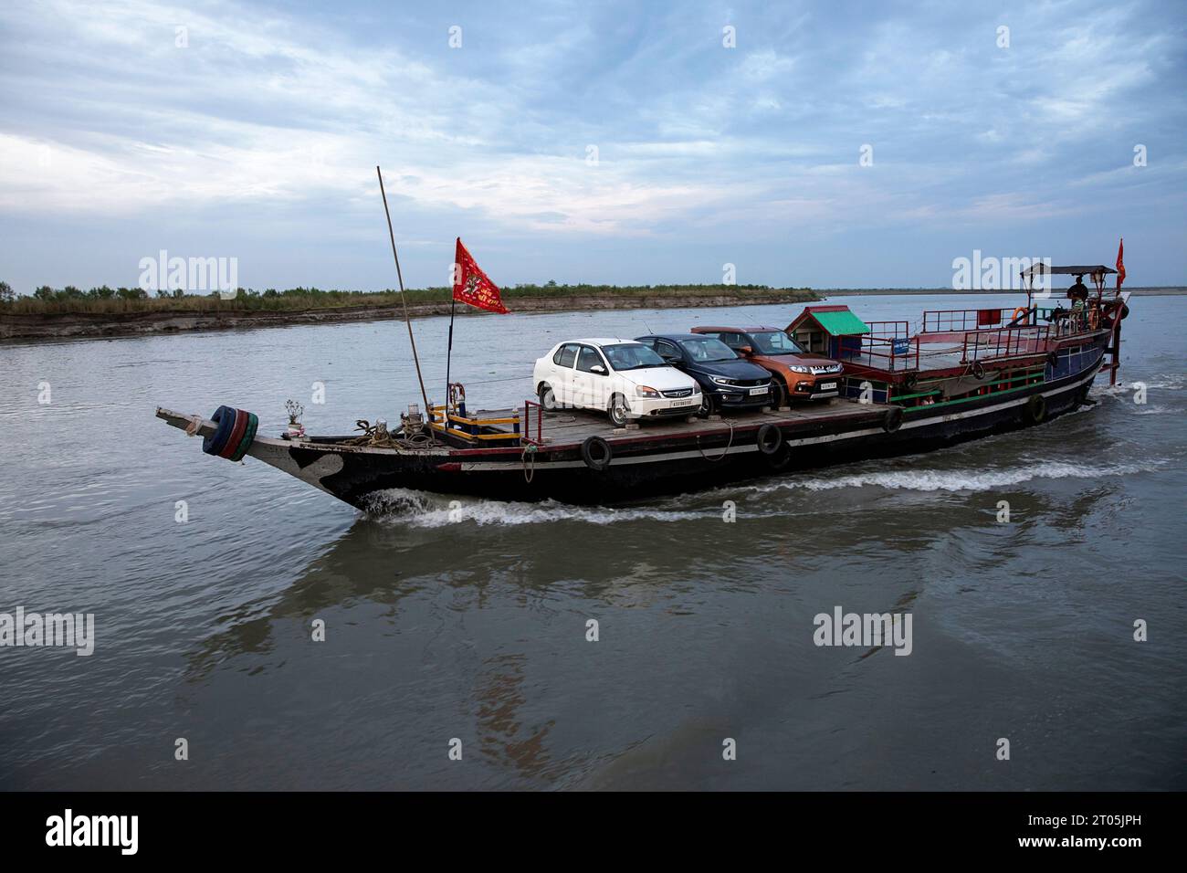 Piccolo traghetto in legno locale, non molto sicuro, sul fiume Brahmaputra, che trasporta auto, merci e persone verso l'isola Majuli, Assam, India Foto Stock