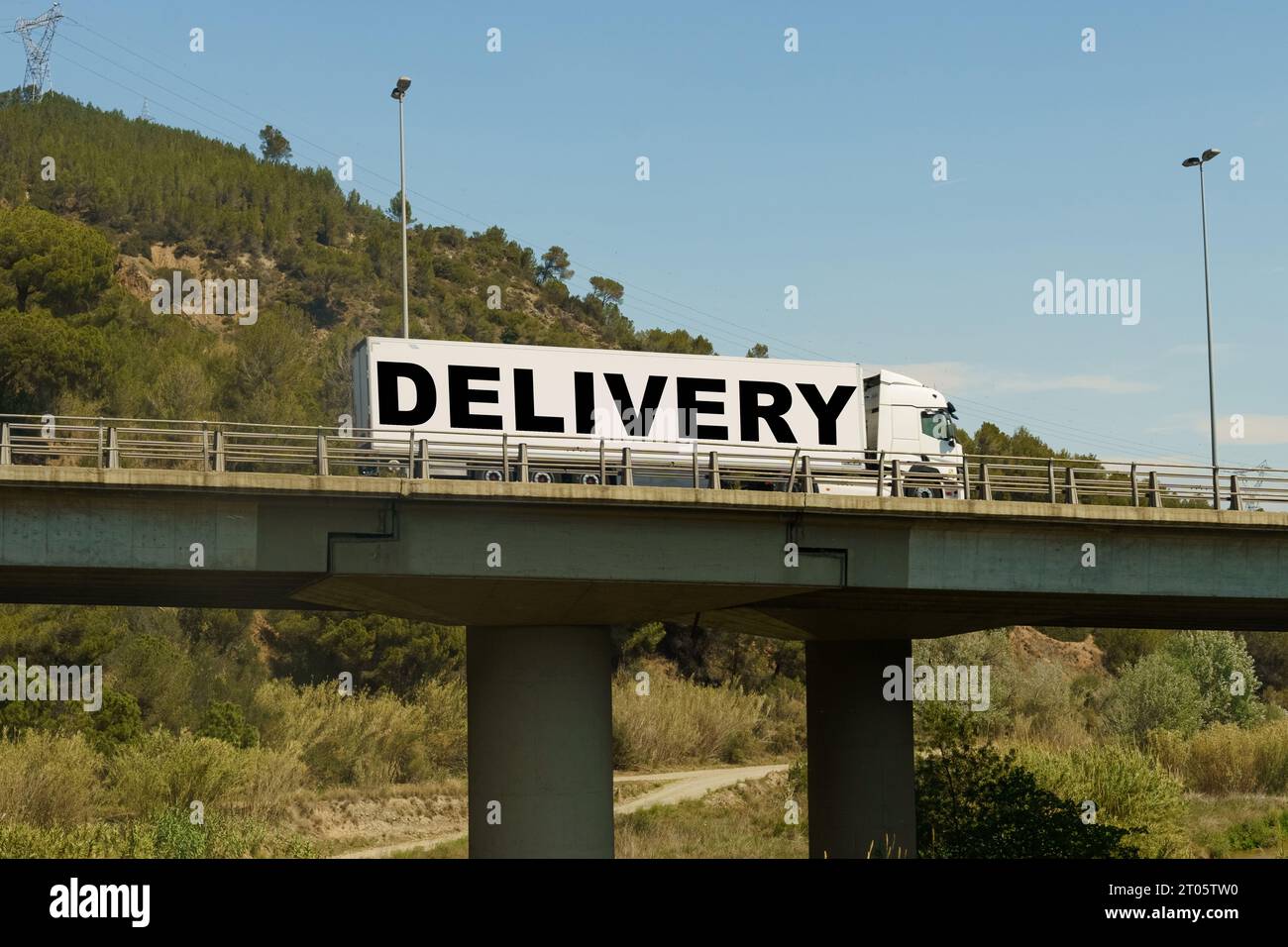 Un veicolo sta attraversando il ponte, con l'iscrizione sul rimorchio - consegna. Concetto di logistica. Foto Stock