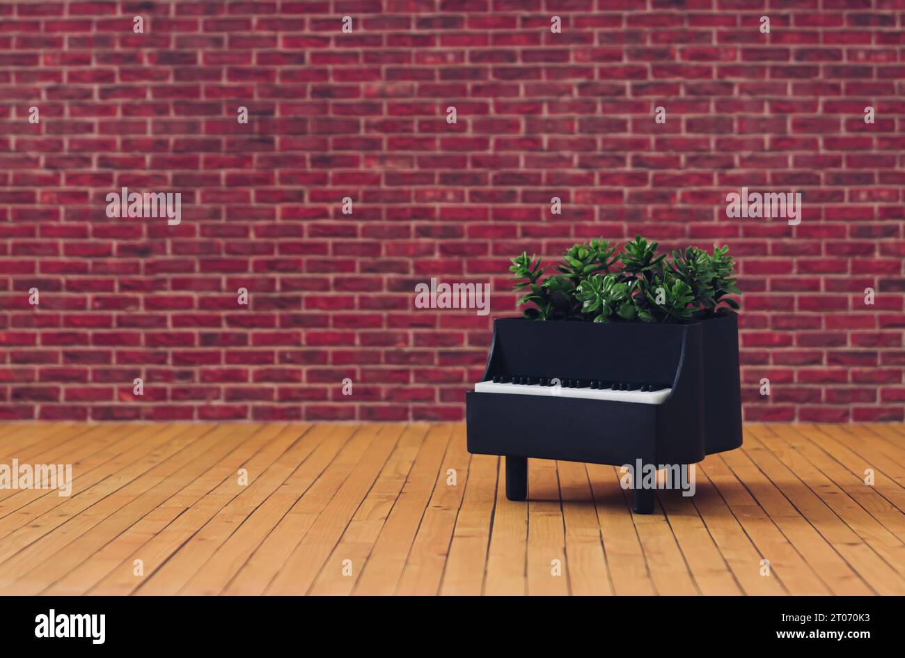 Composizione creativa composta da pianoforte e foglie verdi su sfondo parete di mattoni rossi. Concetto minimale di strumento musicale. Piano alla moda. Foto Stock