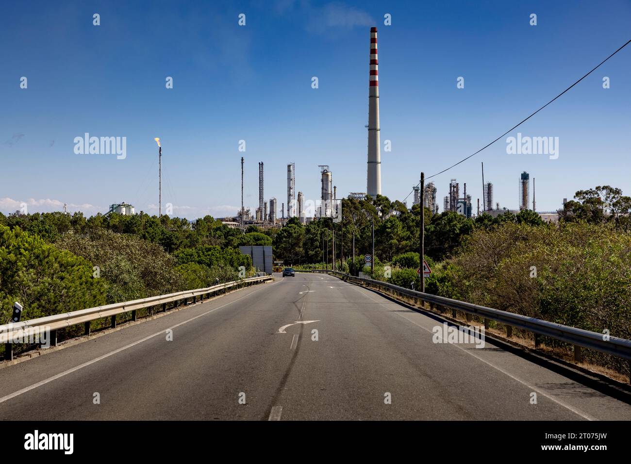 Strada con le torri della centrale elettrica della raffineria Galp di Sines sullo sfondo. Sines in Portogallo. Foto Stock