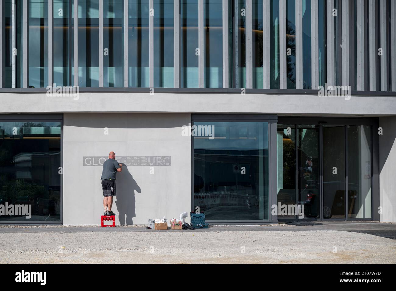 Coburg, Germania. 4 ottobre 2023. Un lavoratore fissa le viti per la scritta "Globe Coburg" sulla facciata esterna del locale culturale Globe. Il Globe sarà un luogo alternativo per il Landestheater Coburg fino alla ristrutturazione del Landestheater. Credito: Daniel Vogl/dpa/Alamy Live News Foto Stock