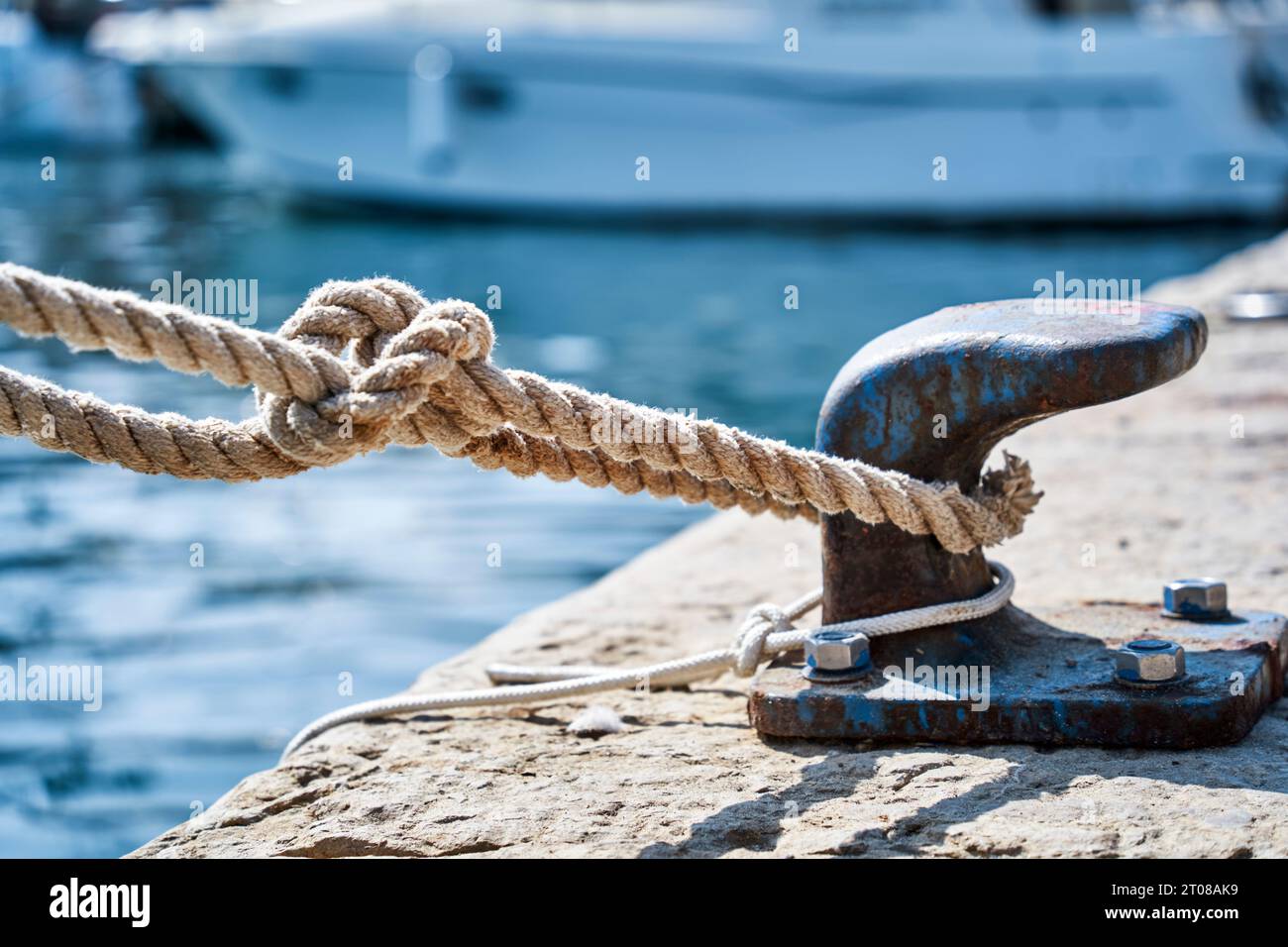 Corda spessa fissata saldamente a un ormeggio sul molo, concetto di coesione sicura Foto Stock