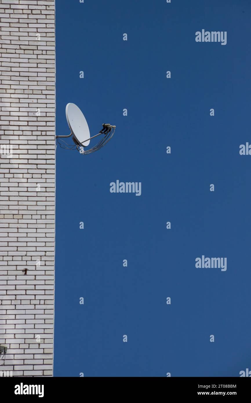 Antenna TV satellitare sulla parete esterna dell'edificio su uno sfondo di cielo Foto Stock