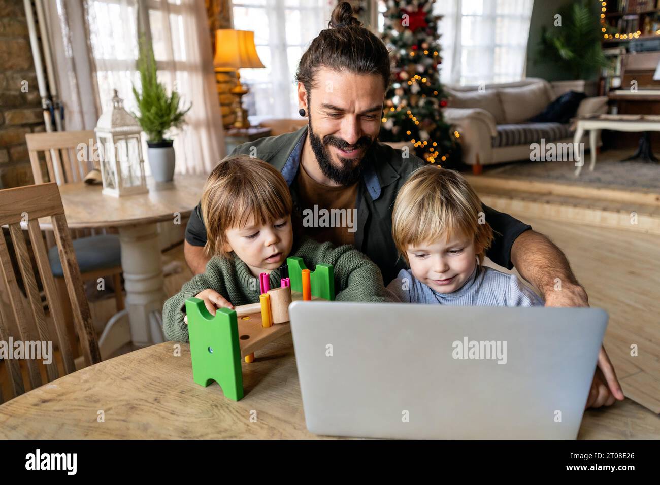 Multi-tasking freelance e concetto di paternità. Padre single che lavora con bambini e computer portatile Foto Stock