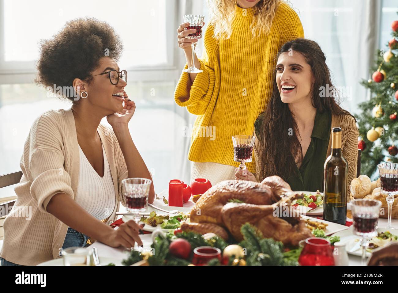 Vista ravvicinata della coppia lgbt e della loro famiglia multiculturale che si diverte al pranzo di Natale Foto Stock
