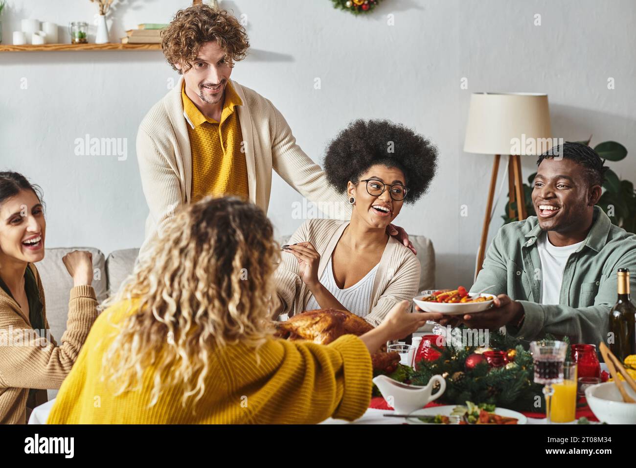 Una grande famiglia allegra si diverte insieme a un tavolo festivo con vino e tacchino, a Natale Foto Stock