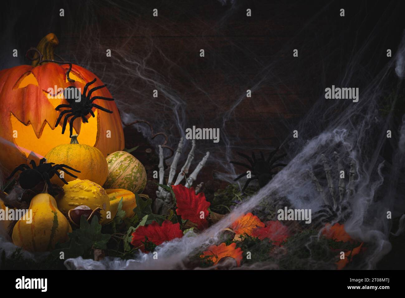 Sfondo di Halloween con zucche, castagne, foglie, decorazioni di Halloween, ragni e mani di scheletro con ragnatele Foto Stock