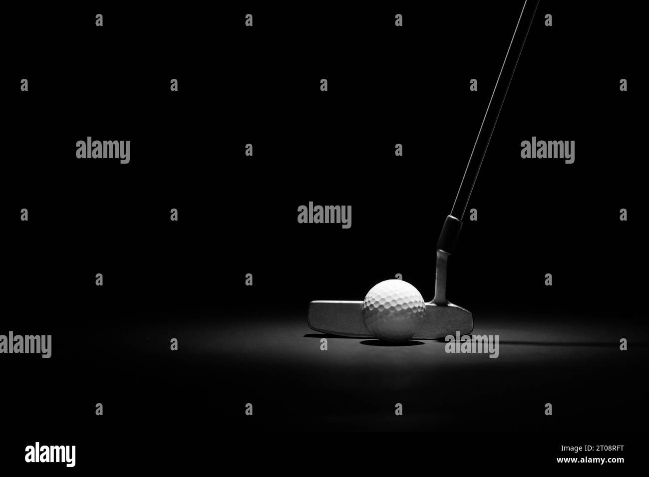 Golf Putter e Ball illuminati su uno sfondo nero con spazio copia Foto Stock