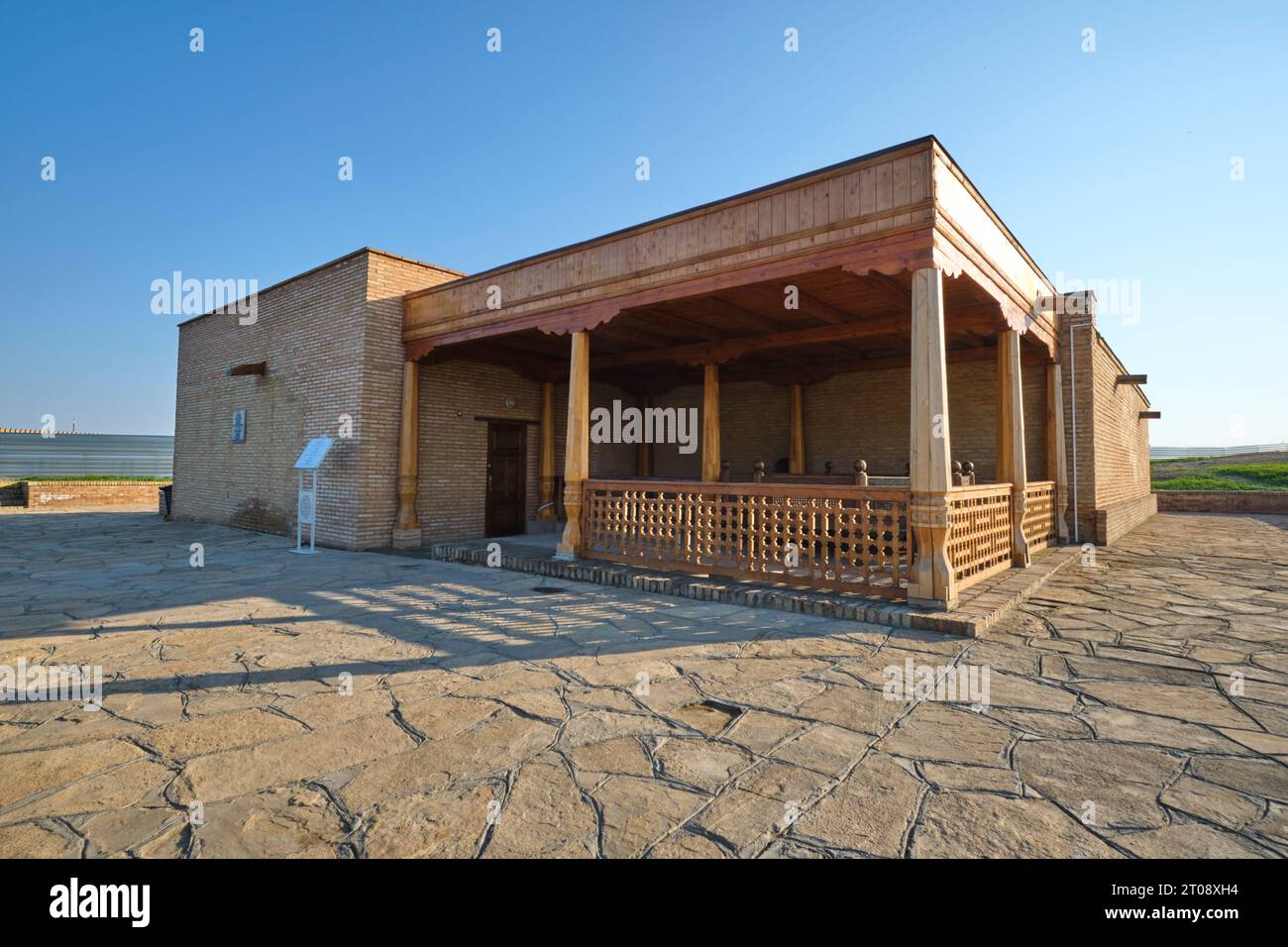 Vista esterna della modesta facciata di mattoni abbronzati con portico d'ingresso e colonne in legno intagliato. Nel complesso Oriental Bath in Turkestan, Kazakhsta Foto Stock