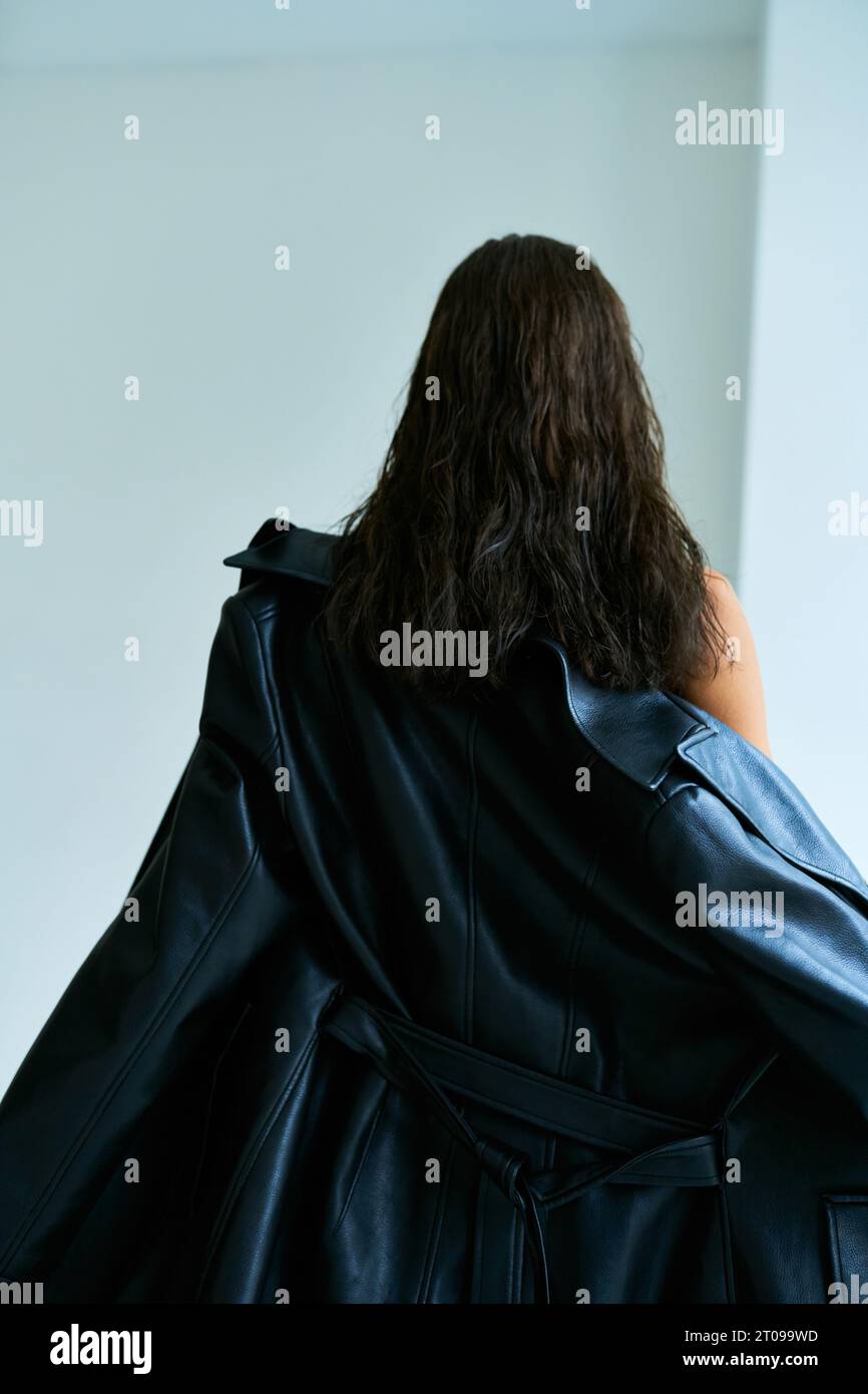 vista posteriore di una donna elegante con capelli bruna in pelle nera, modello alla moda Foto Stock