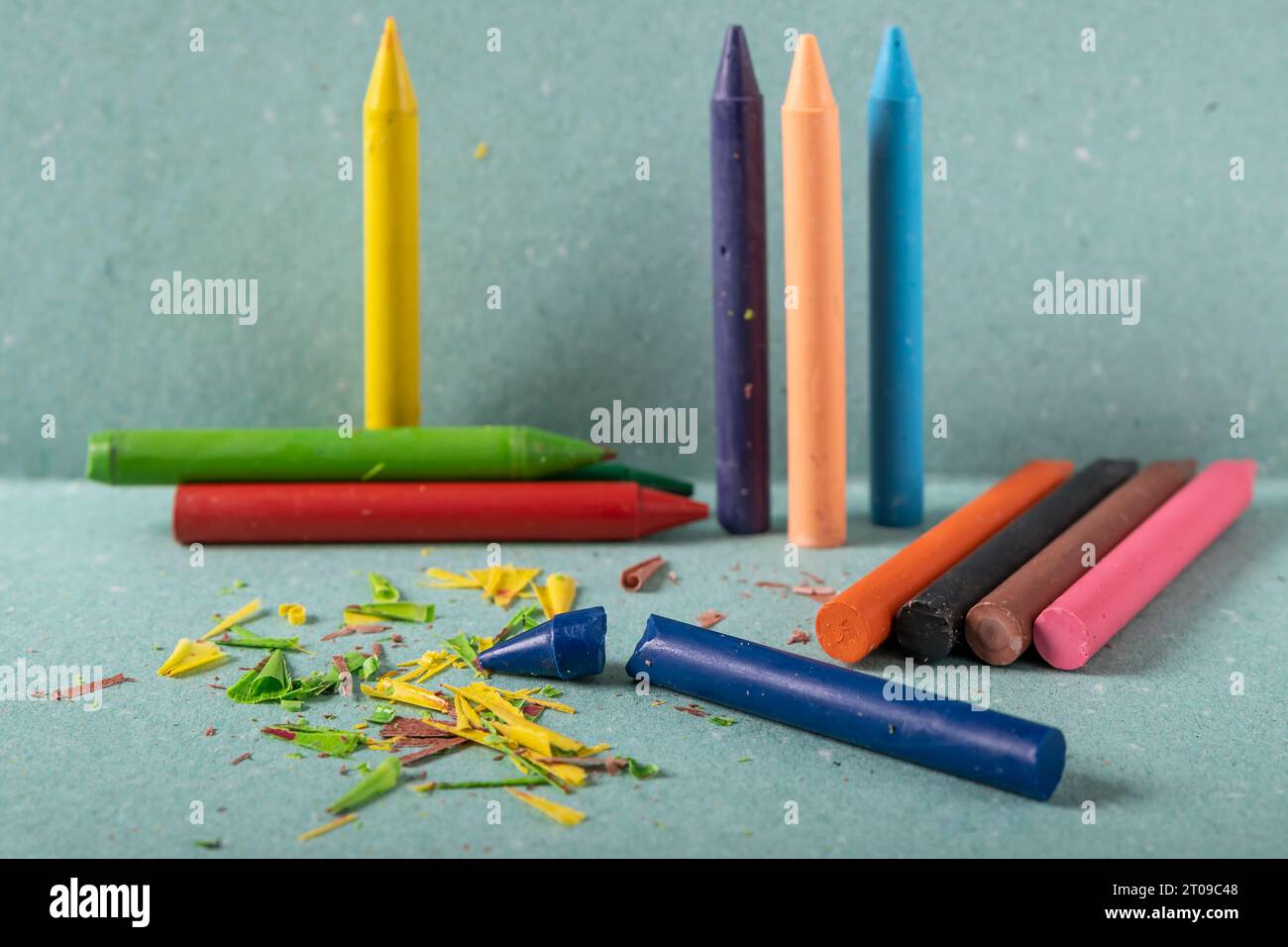 Una serie di pastelli di cera dai colori vivaci sono disposti su un supporto verde e su uno sfondo Foto Stock